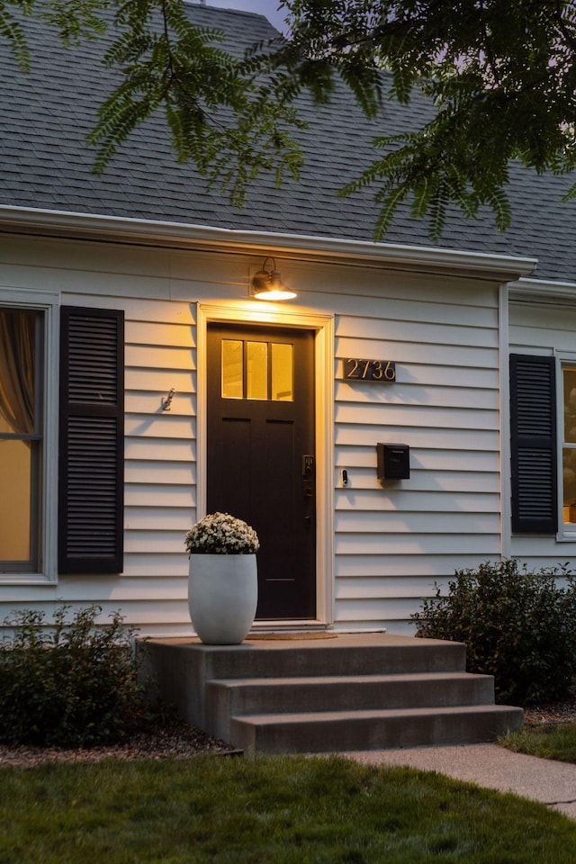 view of exterior entry with a shingled roof