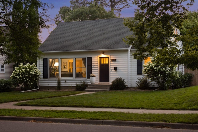 cape cod house with a shingled roof and a front yard