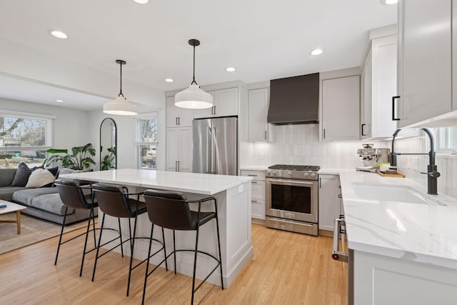 kitchen with a sink, custom range hood, a kitchen bar, high quality appliances, and open floor plan