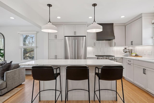 kitchen featuring stainless steel appliances, open floor plan, tasteful backsplash, and wall chimney exhaust hood