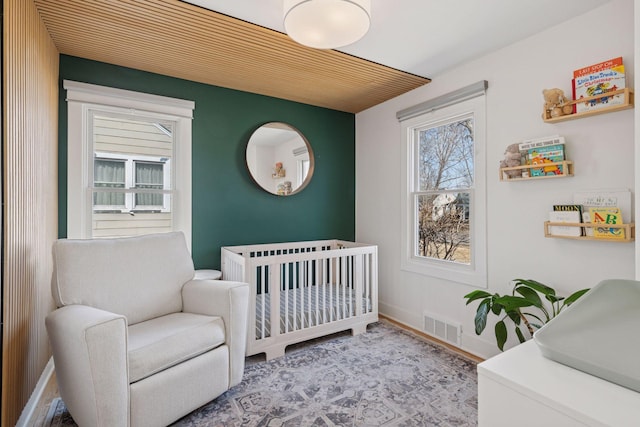 bedroom with visible vents, a crib, and baseboards