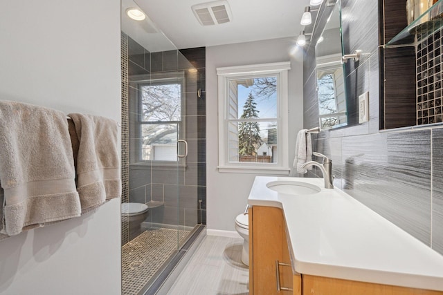 full bath featuring visible vents, a shower stall, baseboards, toilet, and vanity