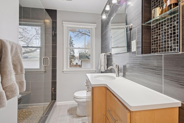 bathroom with baseboards, toilet, a stall shower, and vanity