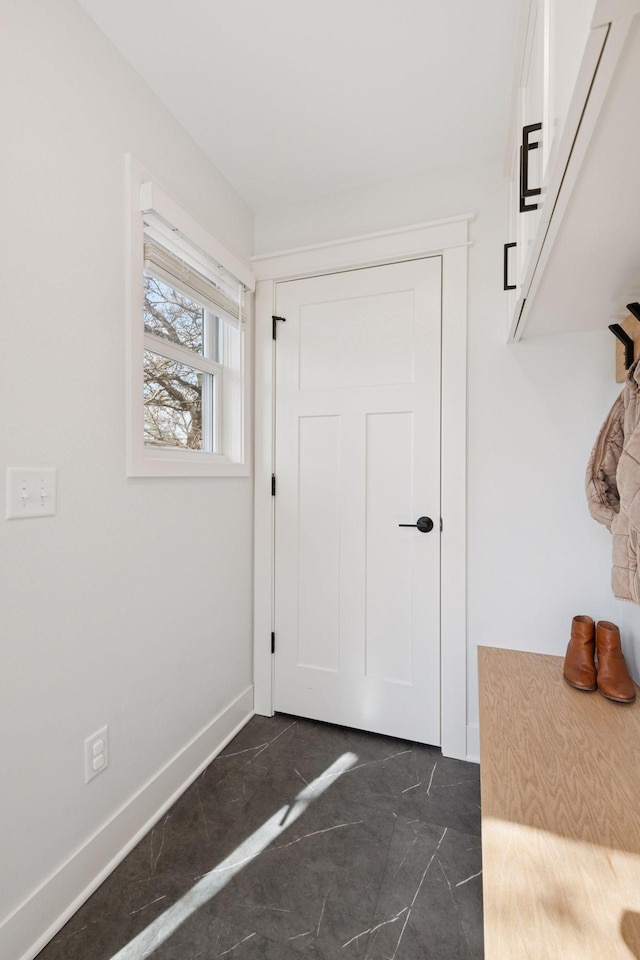 doorway to outside featuring baseboards and marble finish floor