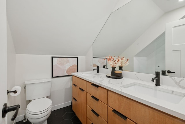 full bathroom with double vanity, toilet, lofted ceiling, and a sink