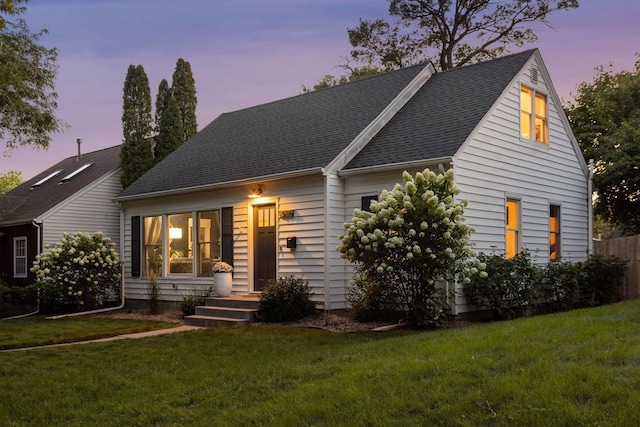 view of front of house with a lawn and roof with shingles