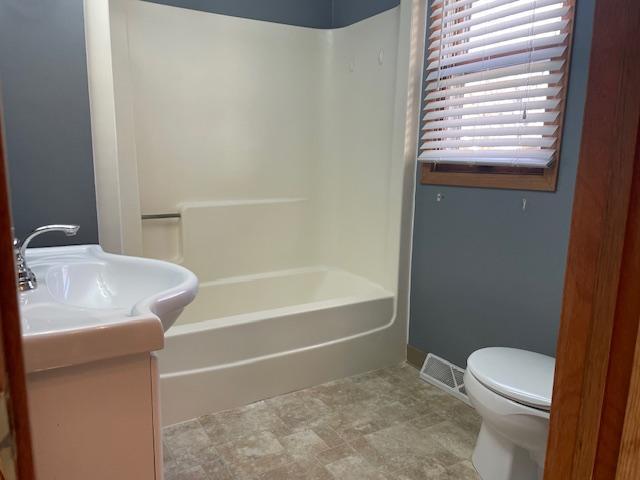 bathroom featuring vanity, baseboards, visible vents, shower / tub combination, and toilet