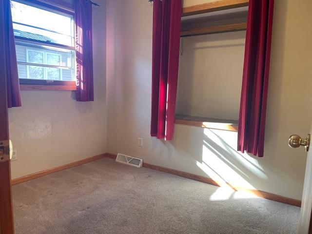 spare room featuring carpet, visible vents, and baseboards