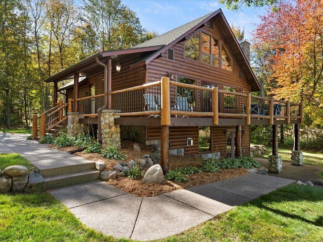 view of side of home featuring a wooden deck, a chimney, and faux log siding