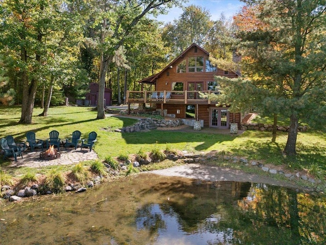 back of property featuring a yard, french doors, a fire pit, a deck, and a patio area