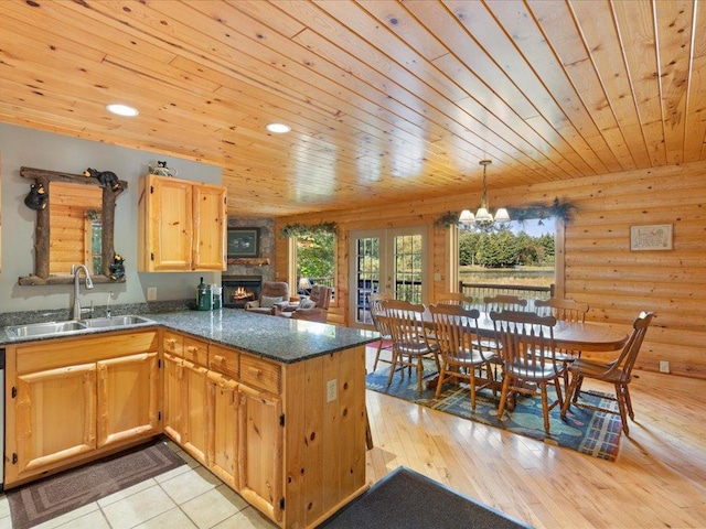 kitchen featuring log walls, a peninsula, a sink, wood ceiling, and light wood-style floors