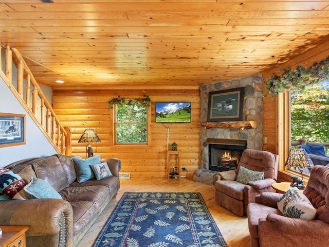 living room with hardwood / wood-style floors, stairway, a fireplace, wooden ceiling, and rustic walls