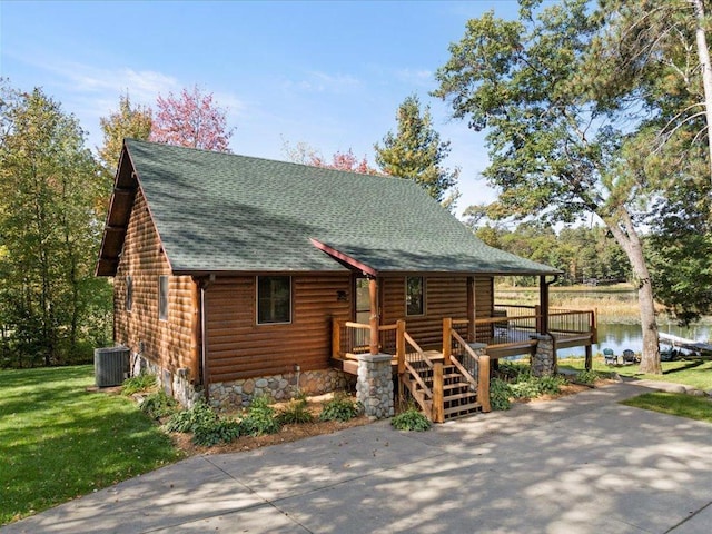 view of front of house with log veneer siding, a water view, central AC, roof with shingles, and a front yard