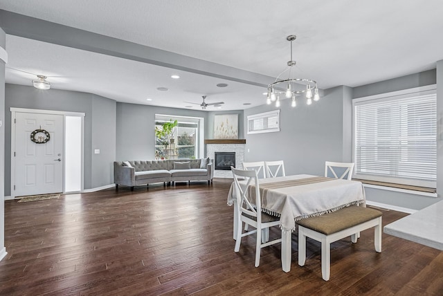 dining space with dark wood-type flooring, baseboards, a stone fireplace, recessed lighting, and a ceiling fan