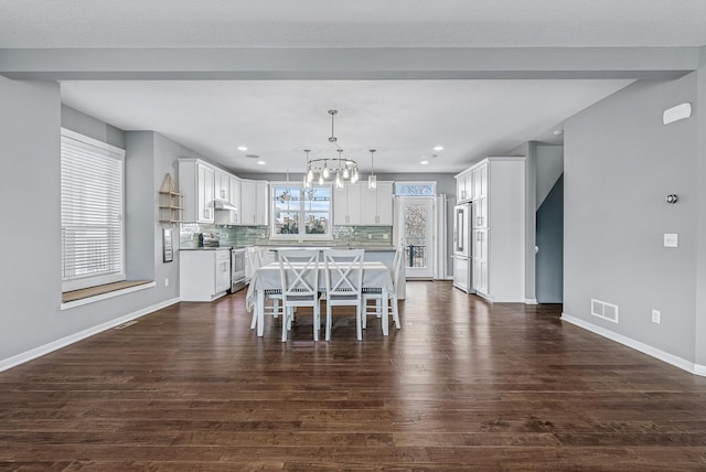 unfurnished dining area with dark wood-style floors, visible vents, baseboards, an inviting chandelier, and recessed lighting