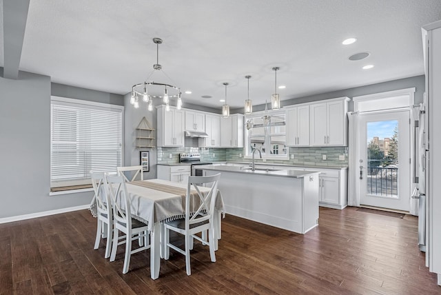 kitchen featuring dark wood finished floors, electric stove, a kitchen island with sink, and a sink