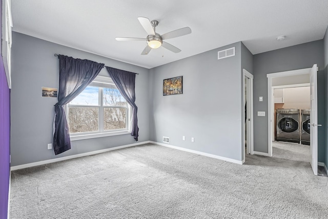 carpeted empty room featuring visible vents, washing machine and dryer, a ceiling fan, and baseboards