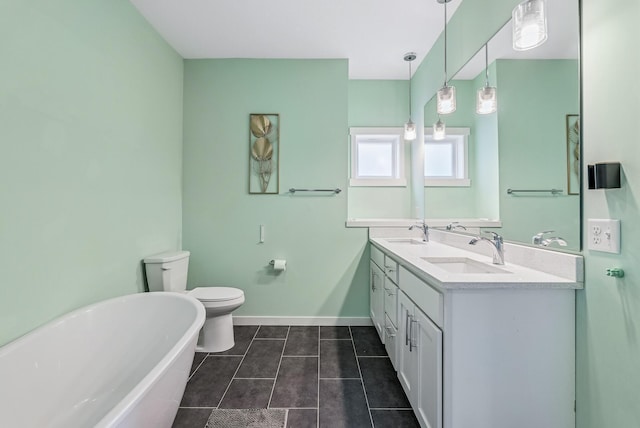 bathroom with a freestanding bath, tile patterned floors, baseboards, and a sink