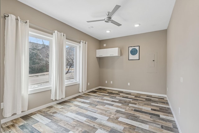 empty room featuring electric panel, recessed lighting, light wood finished floors, baseboards, and ceiling fan