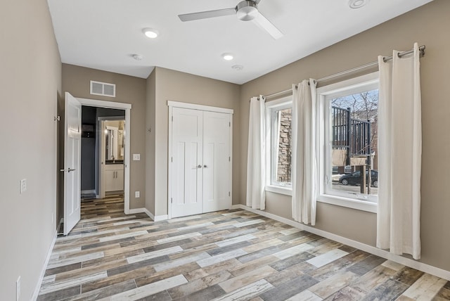 unfurnished bedroom featuring visible vents, baseboards, a closet, and light wood-style flooring