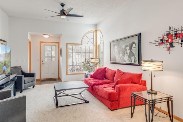 living room with ceiling fan, baseboards, a textured ceiling, and carpet flooring