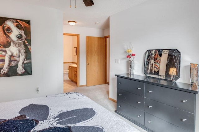 bedroom with light carpet, ensuite bath, and baseboards