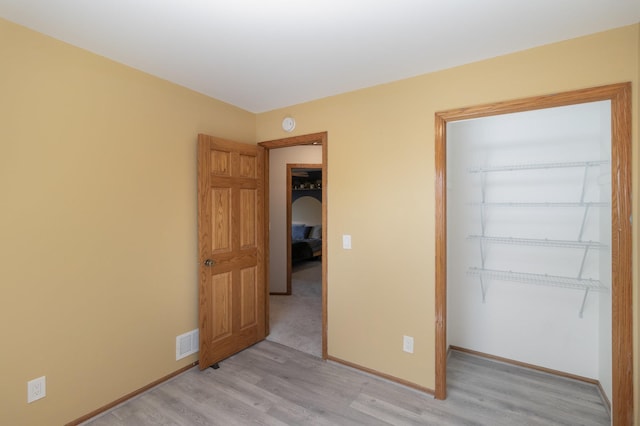 unfurnished bedroom with visible vents, baseboards, a closet, and light wood-style flooring