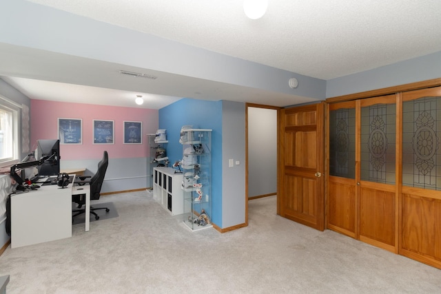 home office with visible vents, carpet floors, a textured ceiling, and baseboards