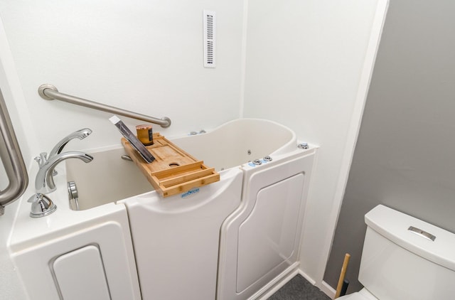 bathroom with a bathtub, visible vents, and toilet