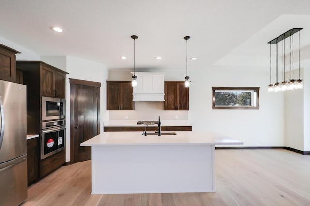 416 Moelter Ln, Hudson, WI 54016 - kitchen with appliances with stainless steel finishes, a sink, light countertops, light wood-style floors, and dark brown cabinetry