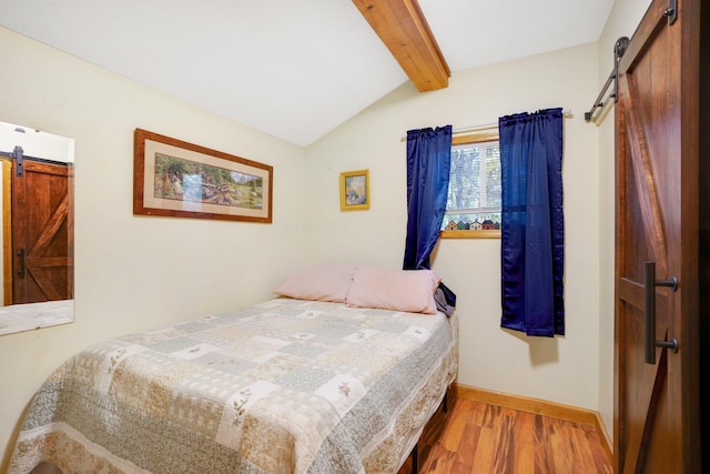 bedroom featuring lofted ceiling with beams, a barn door, wood finished floors, and baseboards