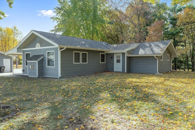 ranch-style house featuring roof with shingles and a front yard