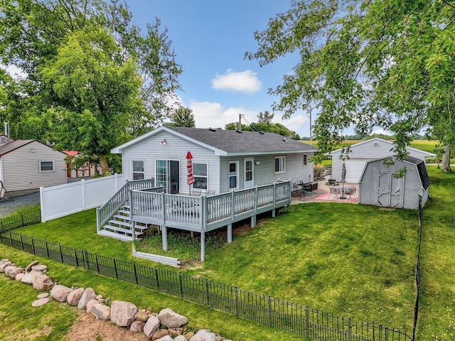 rear view of house with an outbuilding, a yard, a shed, a fenced backyard, and a wooden deck