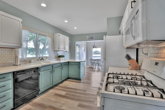 kitchen featuring a peninsula, white appliances, light countertops, light wood finished floors, and green cabinetry