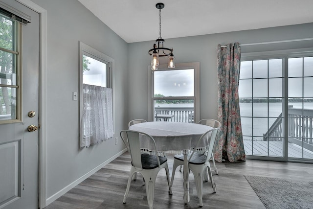 dining space with a water view, wood finished floors, and baseboards