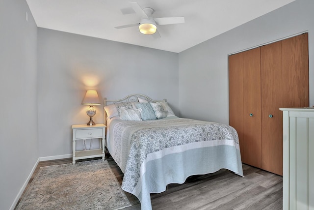 bedroom featuring a closet, wood finished floors, a ceiling fan, and baseboards