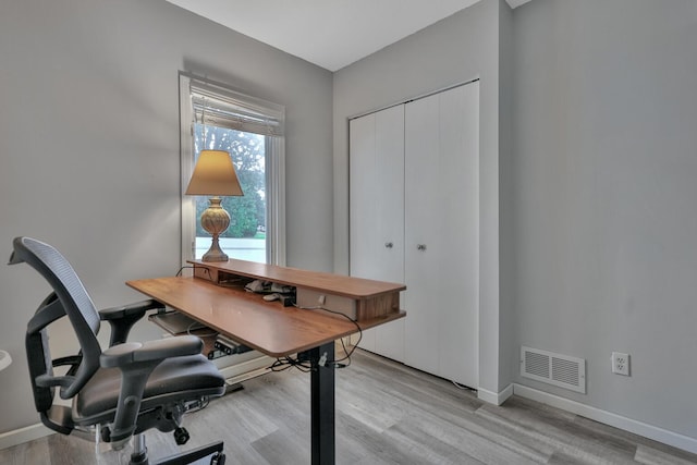 home office with visible vents, light wood-style flooring, and baseboards