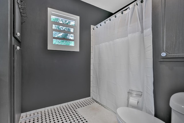 bathroom with toilet, curtained shower, baseboards, and tile patterned floors