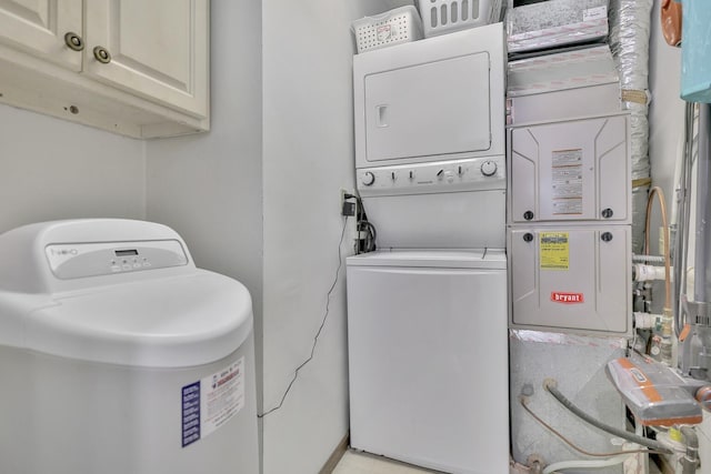 washroom featuring stacked washer and clothes dryer and cabinet space