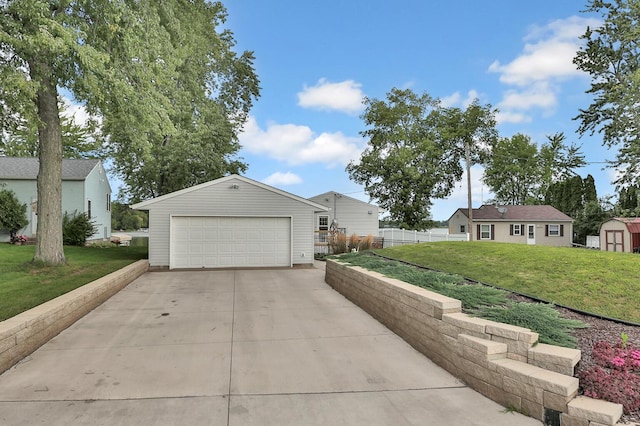 view of front facade with an outbuilding, concrete driveway, fence, and a front lawn