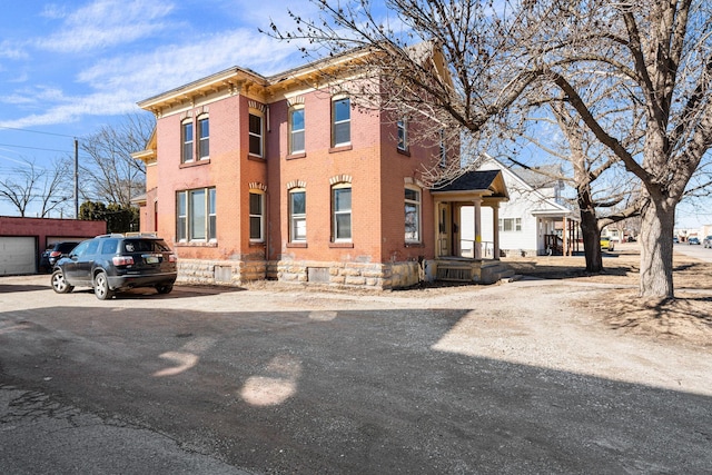 view of front of property featuring an outdoor structure and brick siding