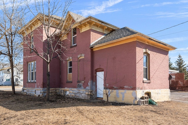 view of side of property with brick siding and a shingled roof