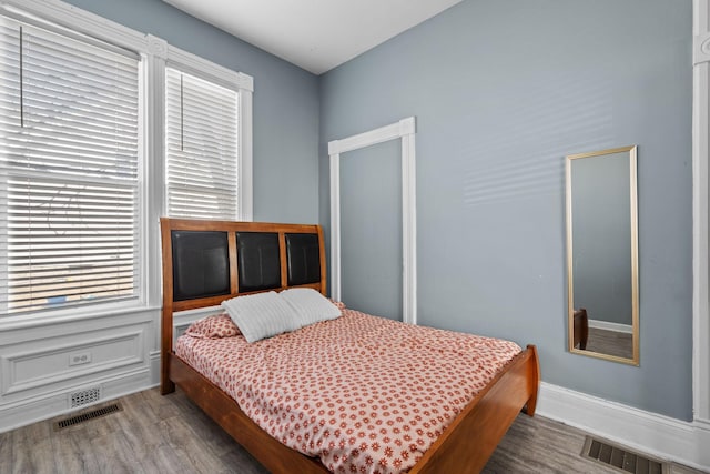 bedroom with visible vents, baseboards, and wood finished floors