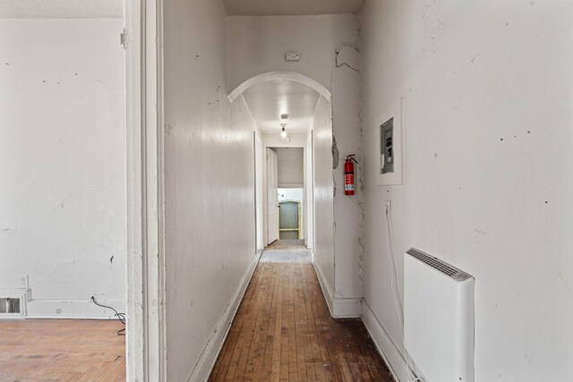 hallway with wood-type flooring, visible vents, arched walkways, and baseboards