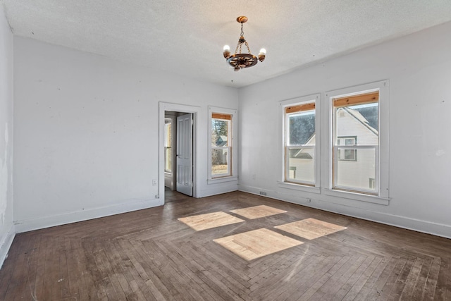 unfurnished room featuring a chandelier, a textured ceiling, hardwood / wood-style flooring, visible vents, and baseboards