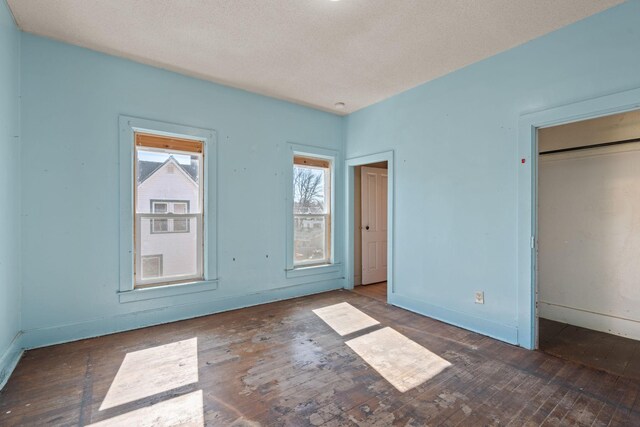 unfurnished bedroom featuring a textured ceiling, hardwood / wood-style flooring, and baseboards