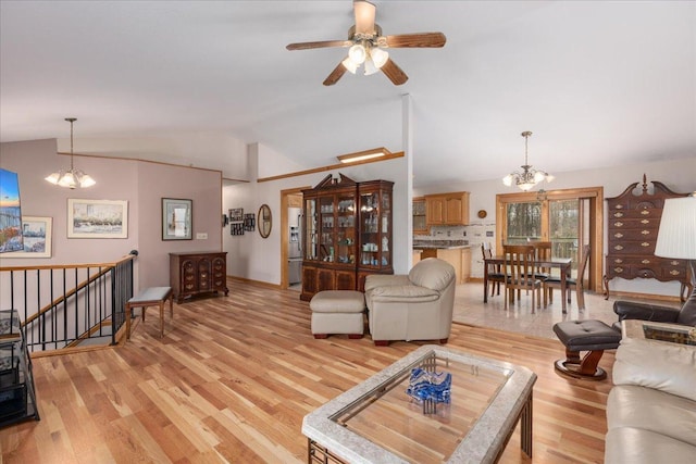 living room featuring vaulted ceiling, ceiling fan with notable chandelier, and light wood-style floors