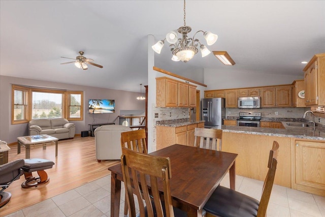 dining area with light tile patterned floors, vaulted ceiling, and ceiling fan with notable chandelier