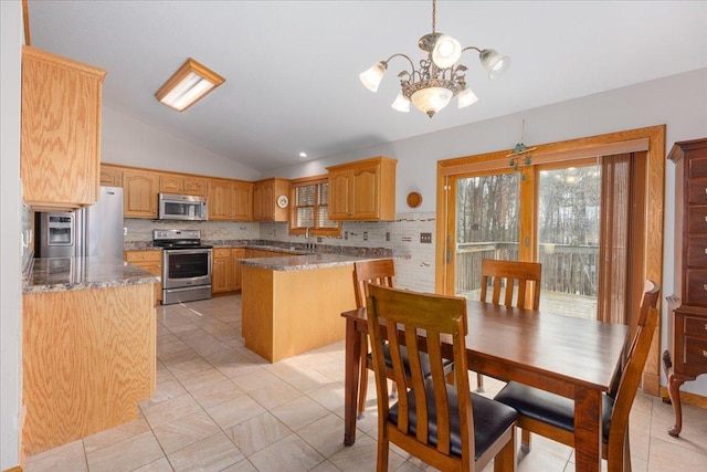 kitchen featuring lofted ceiling, appliances with stainless steel finishes, backsplash, a peninsula, and a sink