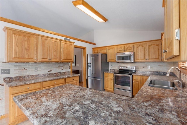 kitchen with visible vents, decorative backsplash, vaulted ceiling, stainless steel appliances, and a sink